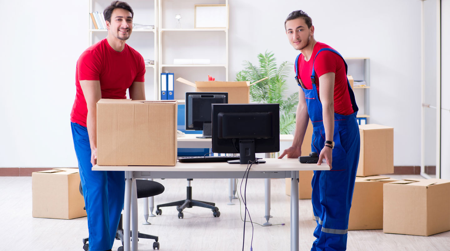 Déménageurs professionnels manipulant avec soin des équipements informatiques emballés lors d'un transfert de locaux d'entreprise